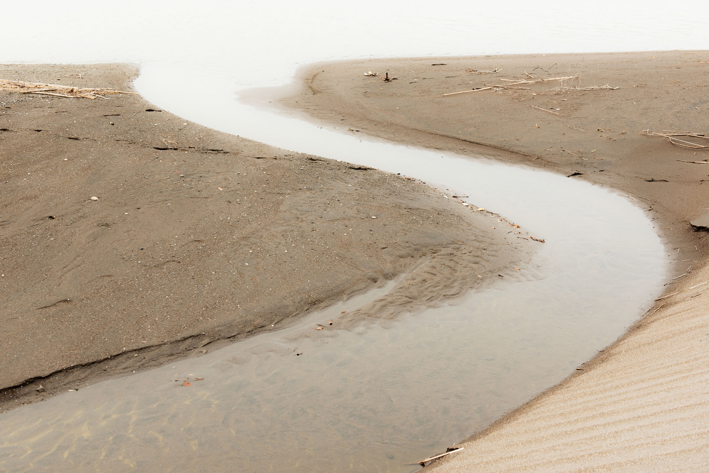 Narrow tidal channel curving through brown sand