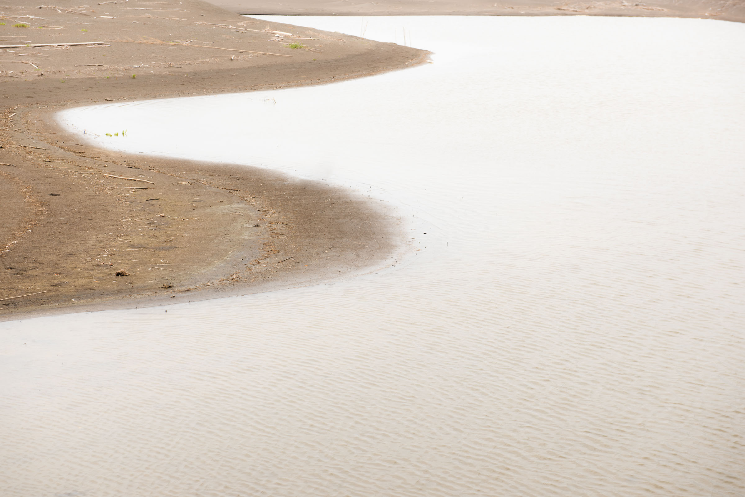 Smooth pale water bordered by curved dark sandbanks