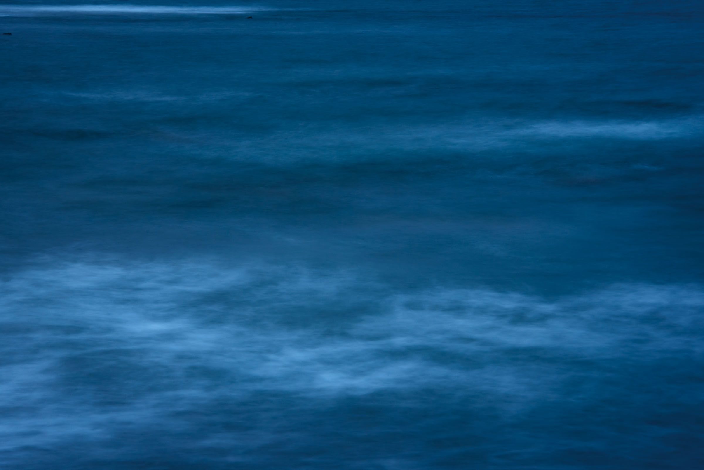 Long-exposure bands of deep blue waves