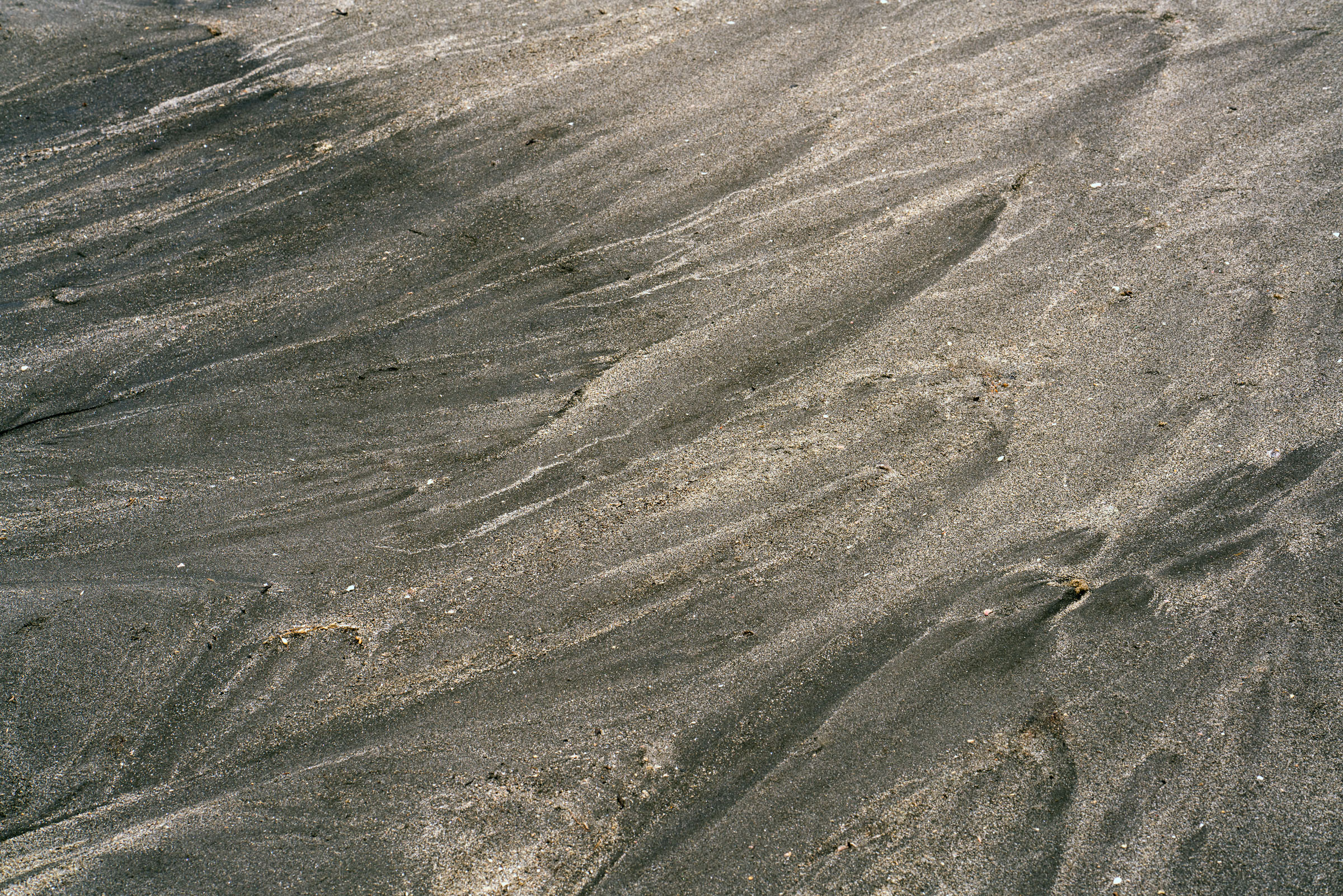 Dark and light sand forming flowing diagonal patterns