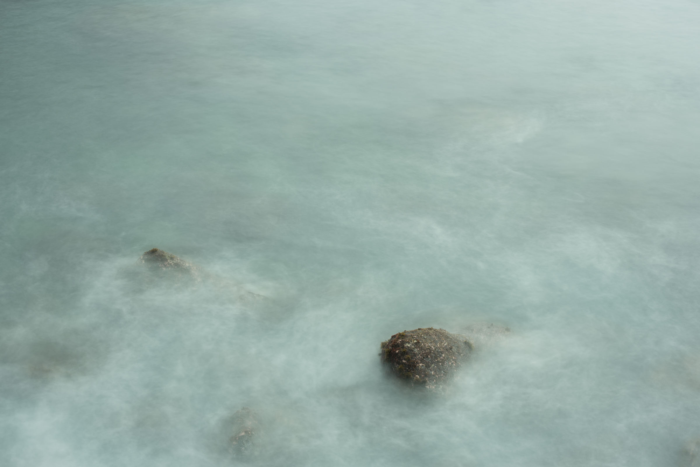 Rocks visible beneath pale moving seawater