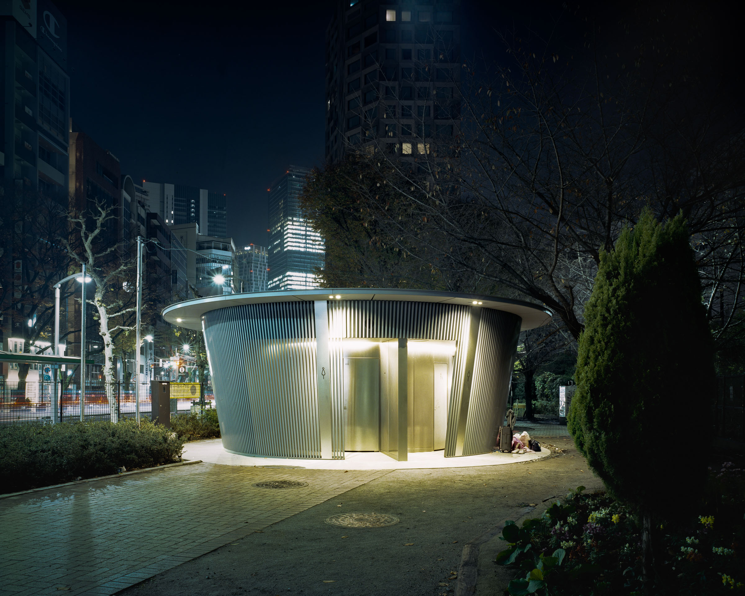 Round louvered public toilet in a city park at night