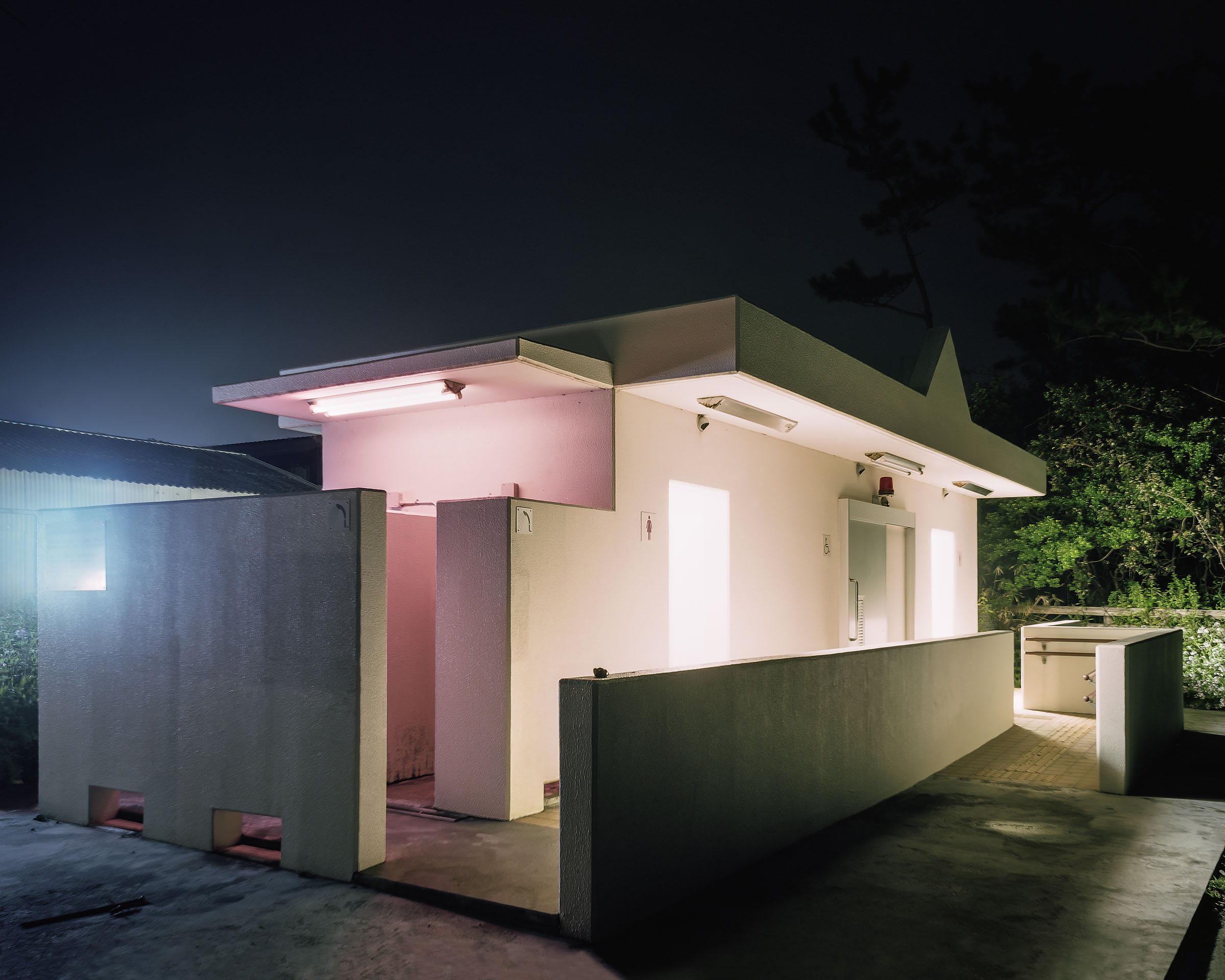Pink-and-white public toilet with open walkways and surrounding walls