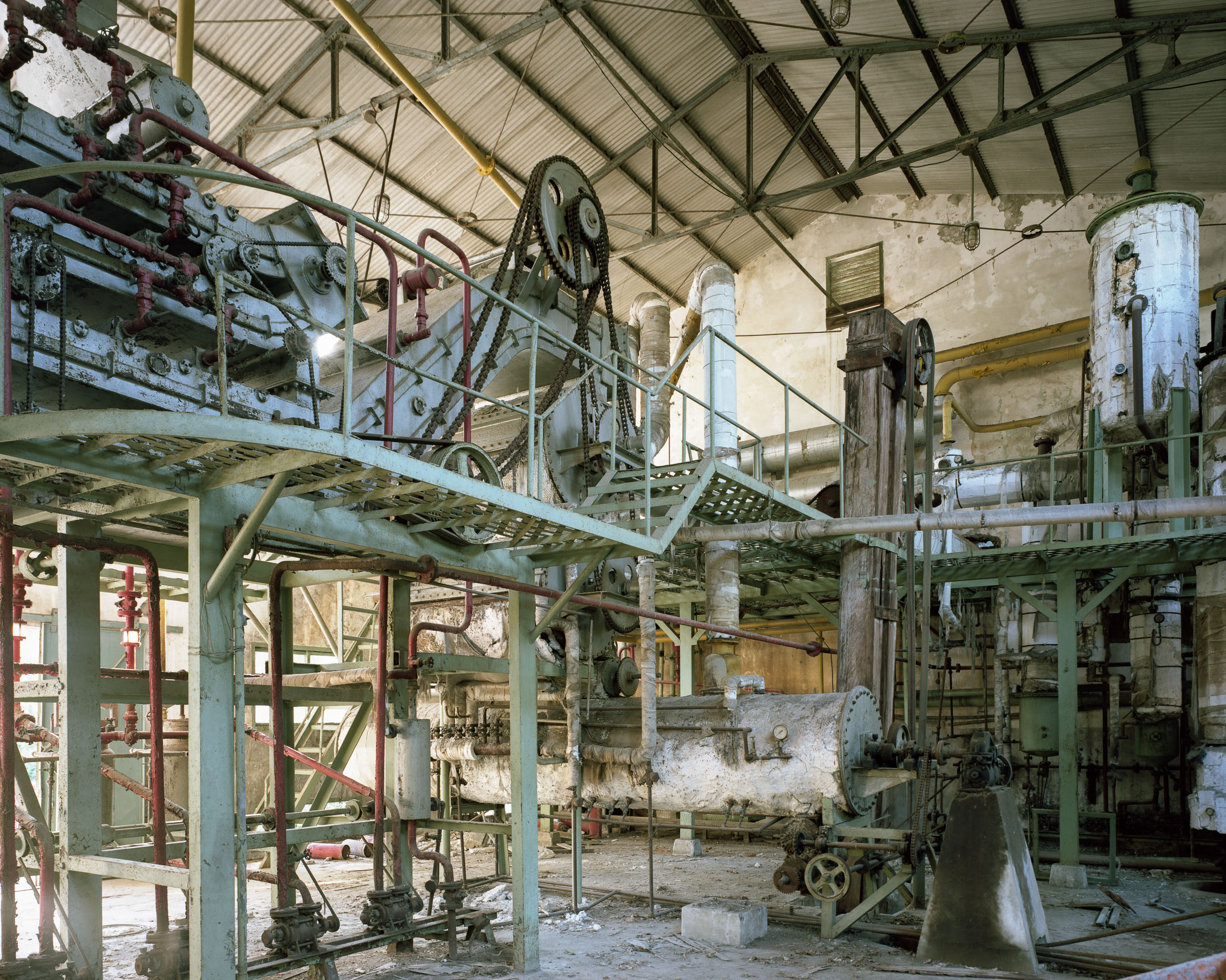 Network of pipes, chains and machinery inside an abandoned factory