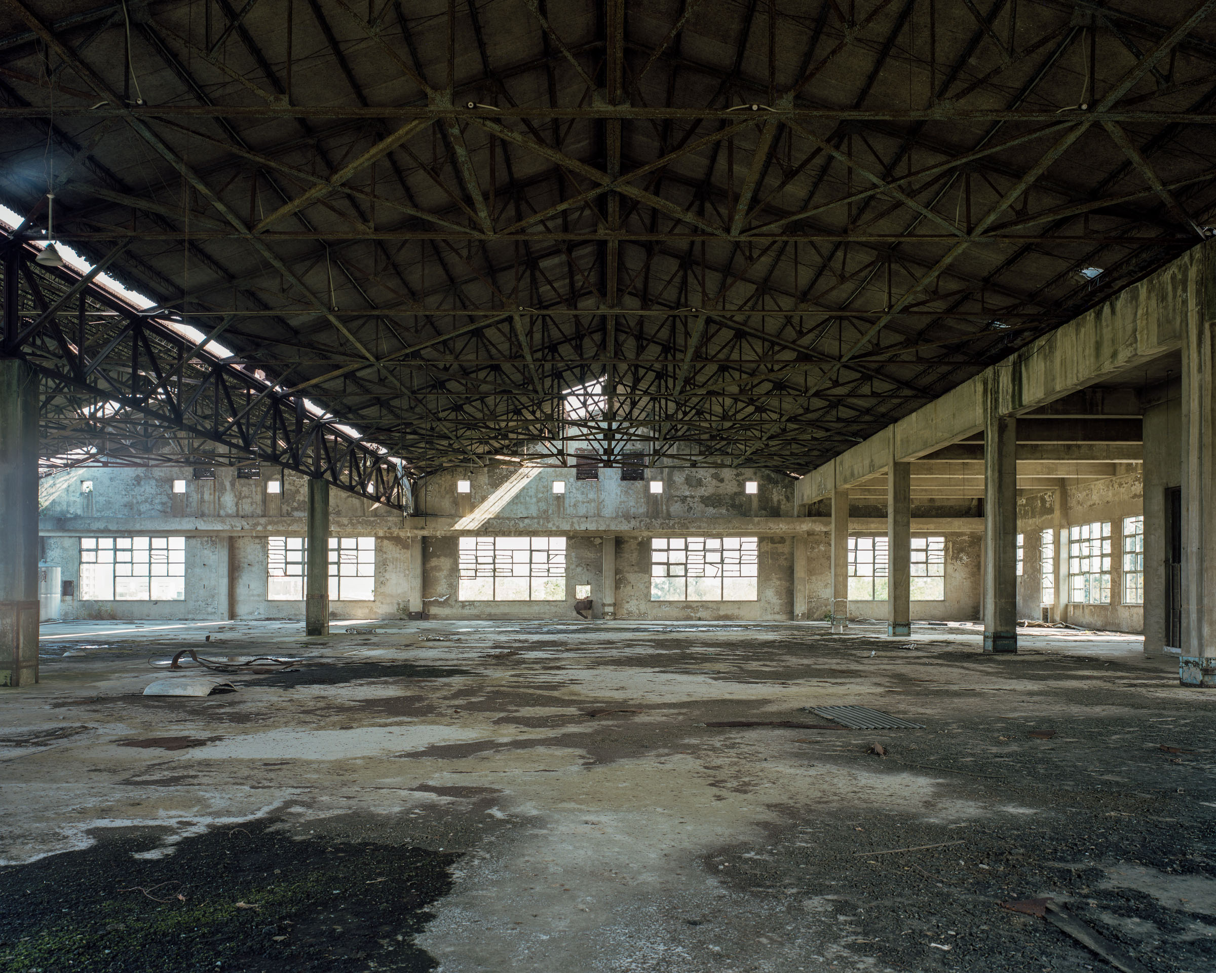 Empty factory hall beneath exposed steel roof trusses