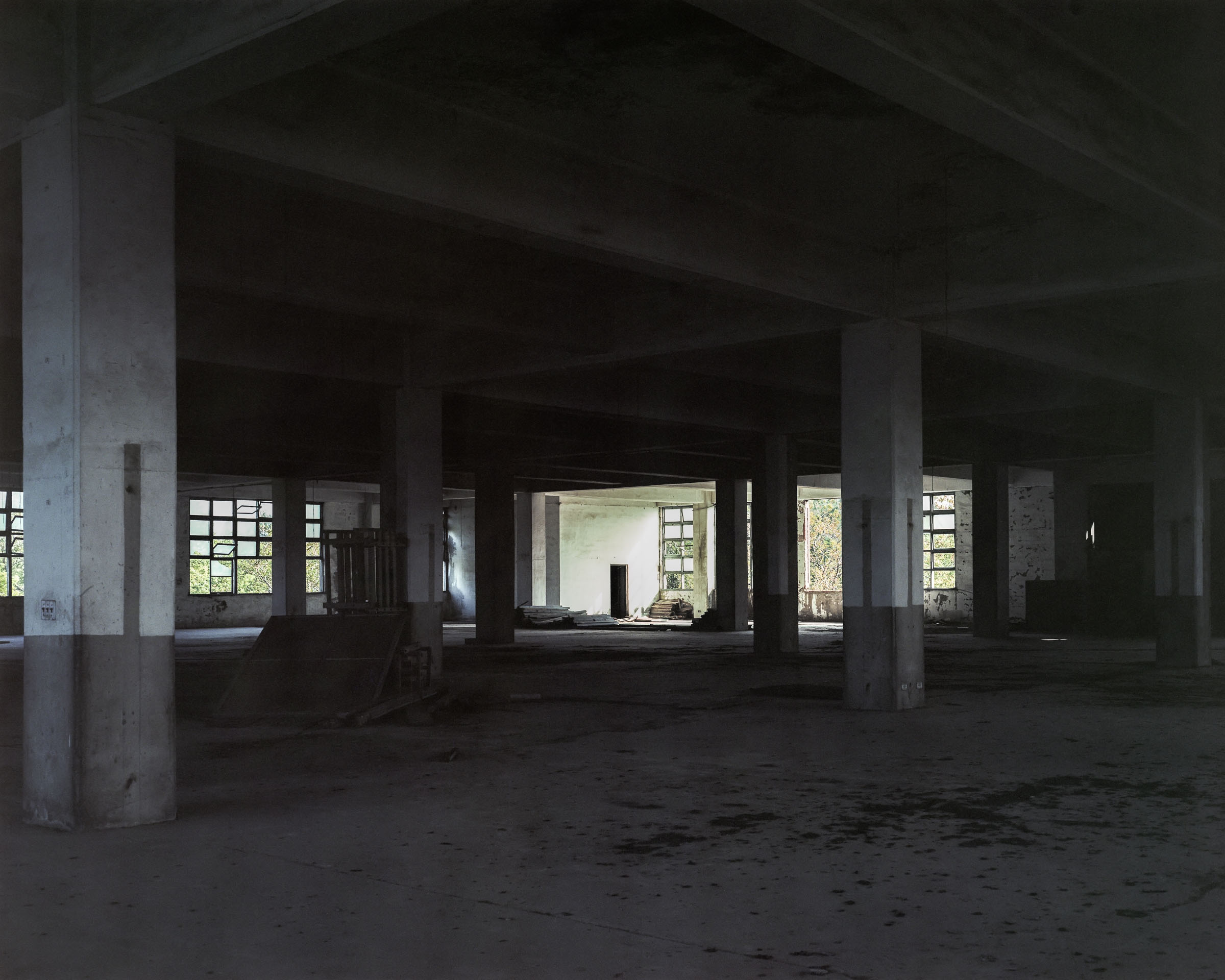 Shadowed factory interior with columns and bright openings