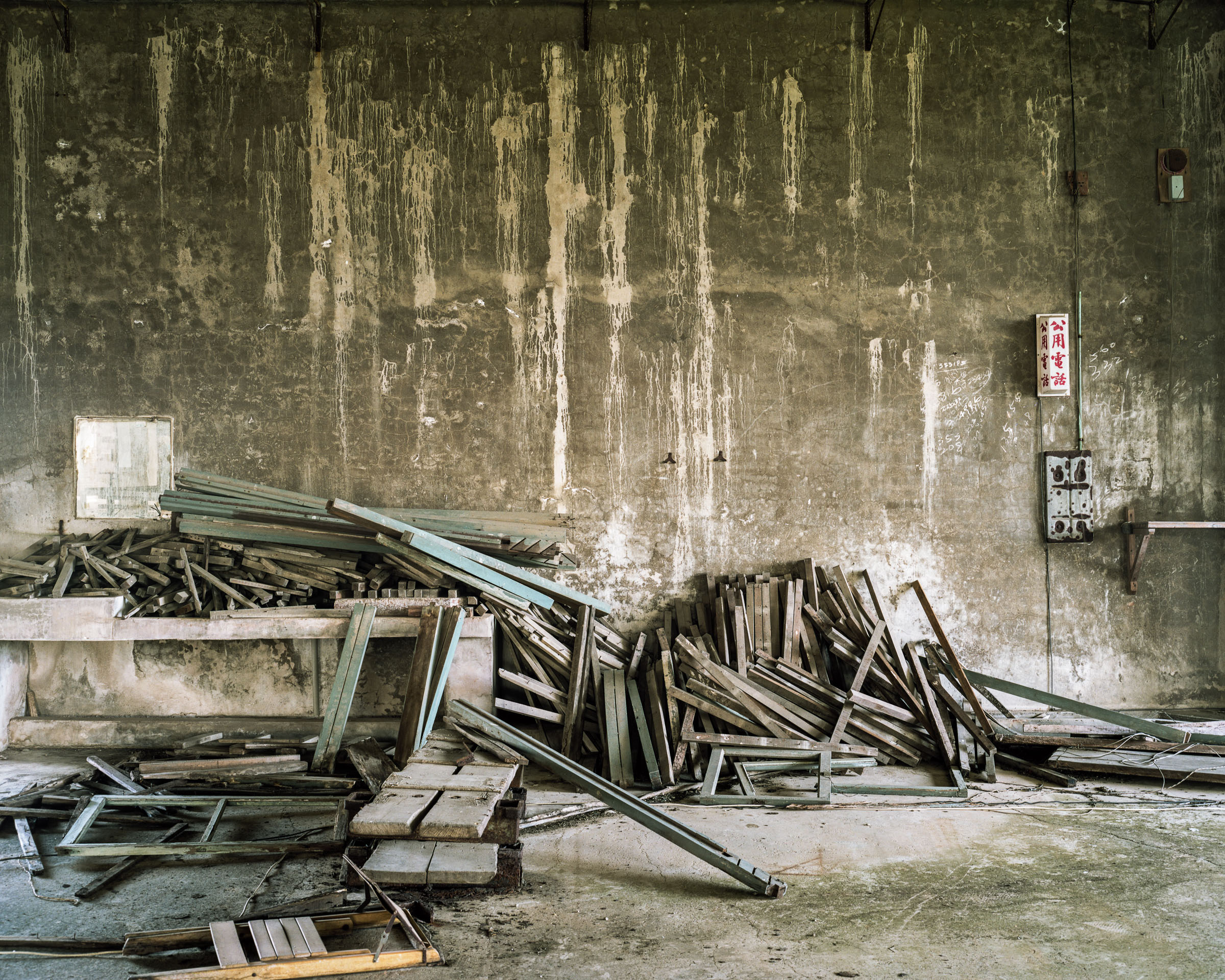 Piles of dismantled wooden frames against a stained concrete wall
